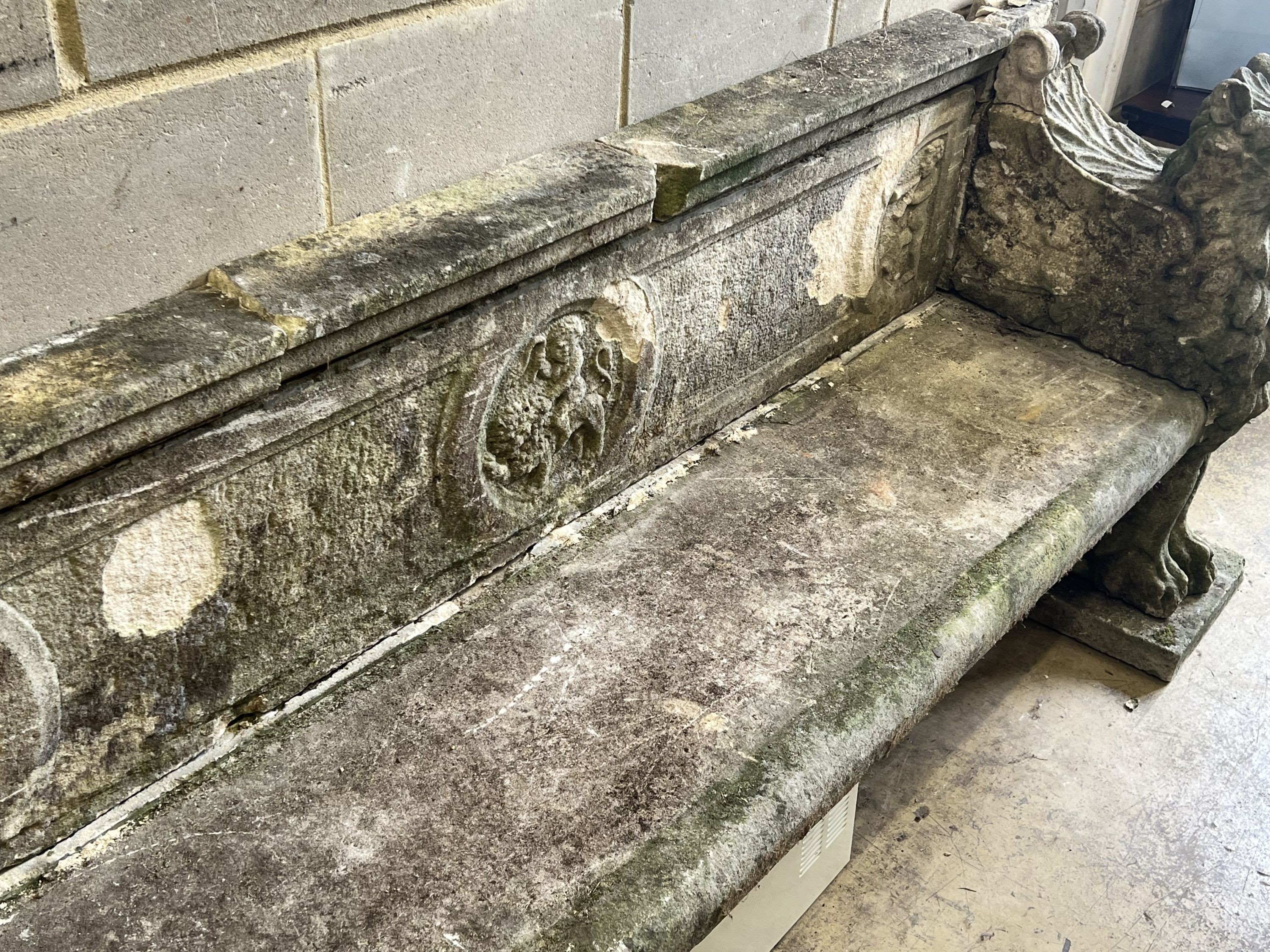 A monumental reconstituted stone winged lion or griffin garden bench, width 250cm depth 66cm height 96cm, in need of restoration